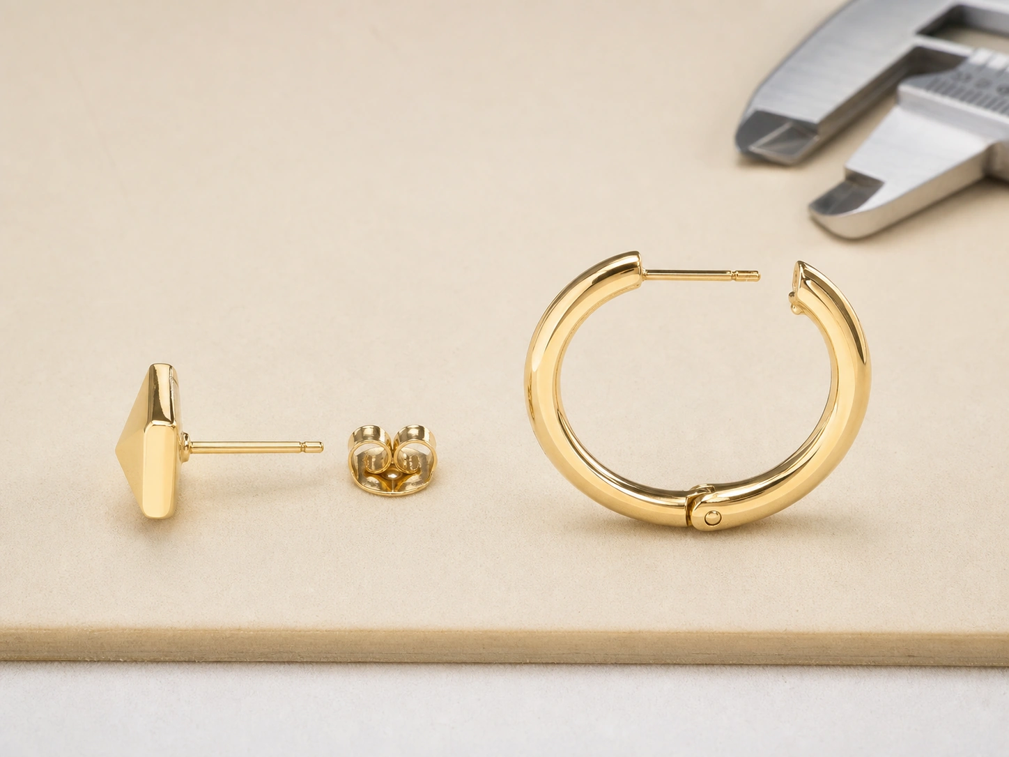 Close-up comparison of a stud earring post and back with a hoop earring hinge and latch